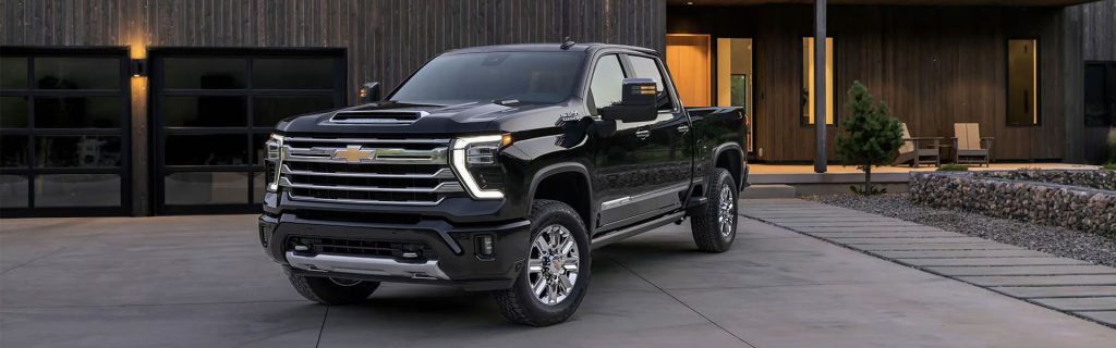 A black Chevrolet Silverado pickup truck parked in front of a modern home