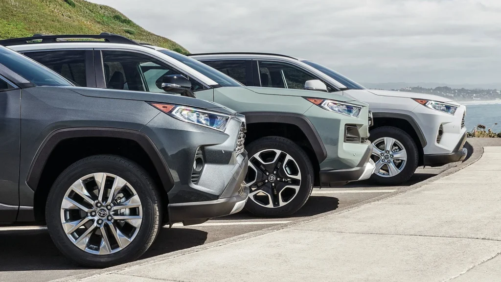 Three Vehicles in different colors parked side by side along a coastal road