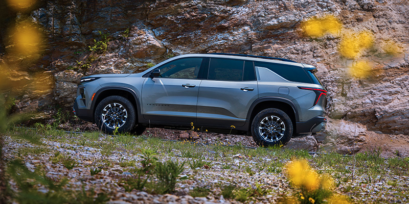 Silver Chevrolet Traverse SUV parked by rocky terrain