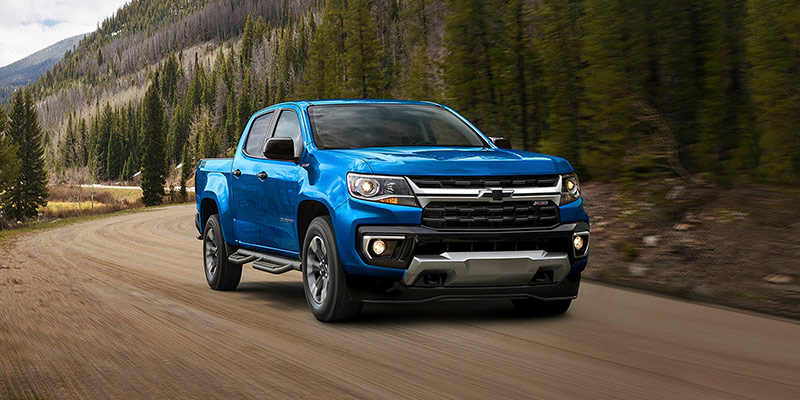 Blue Chevrolet Colorado pickup truck driving on a mountain road.