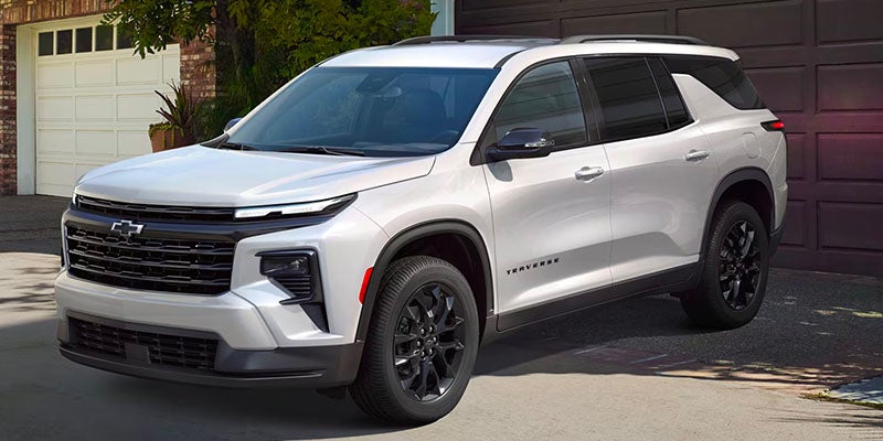 White Chevy Traverse parked outside of a garage door